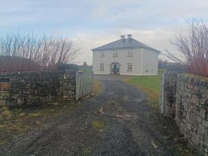a white house with a stone fence and a road at Global Ireland in Williamstown