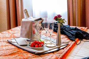 a tray with wine glasses and strawberries on a bed at Logis Hôtel Restaurant La Tête Des Faux in Le Bonhomme