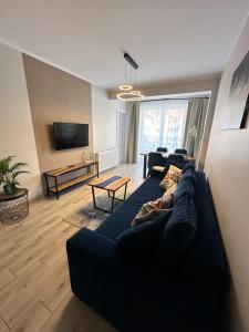 a living room with a blue couch and a tv at Nadmorski czas Darłówko in Darłowo