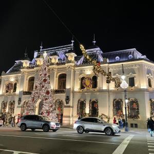 Zwei Autos parkten vor einem Gebäude mit einem Weihnachtsbaum. in der Unterkunft City Hall Apartament in Craiova