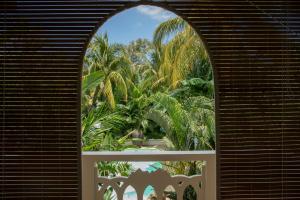 an arched window with a view of palm trees at Maison Tropical in Flic-en-Flac