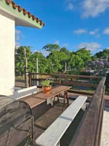 a wooden table and benches on a deck with trees at Hermoso apartamento en el centro de Atlántida in Atlántida