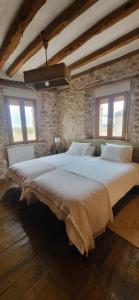 un grande letto in una stanza con due finestre di Casa de las Eras a Valdesimonte Altre 33 foto