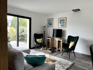 a living room with a couch and chairs and a tv at Maison moderne et chaleureuse, emplacement idéal in Arzon