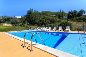 a swimming pool with a bunch of chairs next to it at A1 Outra Vez - Spacious apartment in Carvoeiro