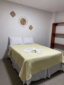 a bedroom with a bed with a yellow blanket at Pousada Pé na Areia in São Miguel dos Milagres