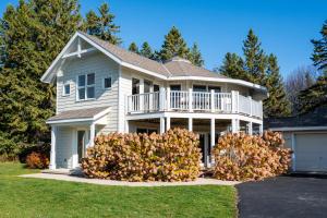 a large white house with a porch and balcony at The Goat and Cherry - Dogs, Fire Pit & Hot Tub, Escape to Sister Bay! in Sister Bay