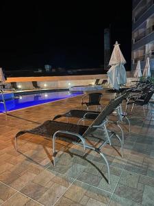 a row of chairs sitting next to a swimming pool at Apartamento pé na areia in Ubatuba