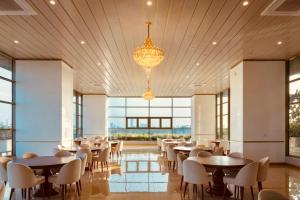 Un comedor con mesas y sillas y ventanas. en The Grand Ward Place - Colombo 7, en Colombo