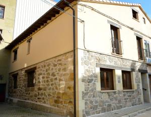 un edificio con una pared de piedra y ventanas en La casa de la abuela Gabina, Duruelo de la Sierra - 12 personas, en Duruelo de la Sierra