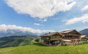 una casa su una collina con le montagne sullo sfondo di Berggasthof Christernreith a Maria Alm am Steinernen Meer