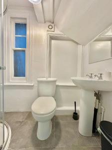Un baño blanco con inodoro y lavabo. en Guesthouse 81, en Londres