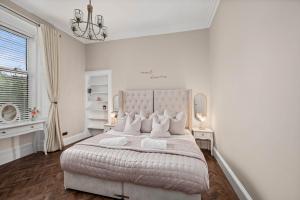 a white bedroom with a large bed and a window at Willowbank in Broughty Ferry