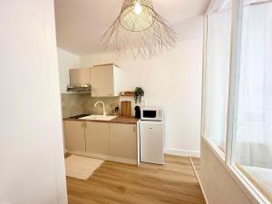 eine Küche mit einem weißen Kühlschrank und einer Mikrowelle in der Unterkunft Mini Loft avec Cinema et Terrasse - Cap D'Agde in Cap d'Agde