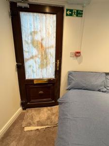 a bedroom with a bed and a door with a window at The Peacock studio 7 mins from Luton airport in Luton