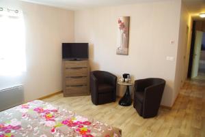 a bedroom with a bed and two chairs and a television at La Grimodière in Ranville