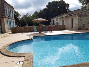 a large blue swimming pool with two chairs and an umbrella at Domaine de Fontcouverte - Gîte in Fontcouverte