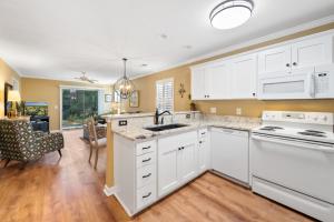 a kitchen with white cabinets and a dining room at 53B Blue Wedge at True Blue condo by Peace Vacations in Pawleys Island