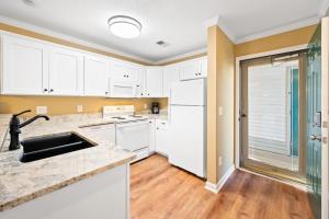 a kitchen with white cabinets and white appliances at 53B Blue Wedge at True Blue condo by Peace Vacations in Pawleys Island
