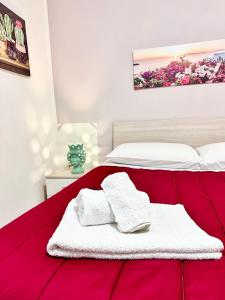 un letto rosso con due asciugamani sopra di Seacily house a Mazara del Vallo