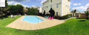 a backyard with a swimming pool and chairs and a building at Anchorage Hotel & Spa in Torquay