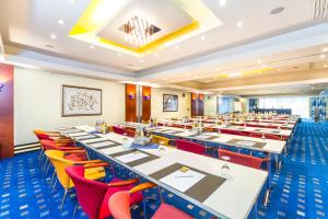 Hotel Fulda Mitte في فولدا: قاعة اجتماعات مع طاولات طويلة وكراسي حمراء