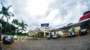 a hotel with cars parked in a parking lot at Hotel Graal Inn Uberaba in Uberaba