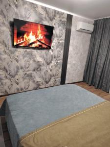 une chambre avec une cheminée et une télévision au mur dans l'établissement Уютная 1 ком кв ЖД Вокзал Консульство РФ, à Uralsk
