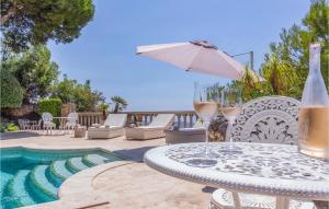 a table with wine glasses and an umbrella next to a pool at Lovely Home In Málaga in Málaga +40 photos