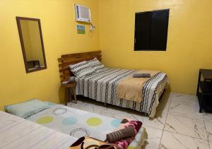 a bedroom with two beds and a mirror and yellow walls at Casa Amarela in Presidente Figueiredo