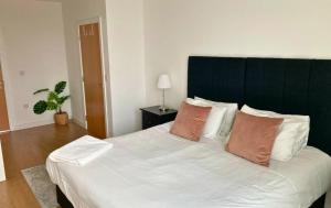 ブラックネルにあるBracknell RWH Stunning Two Bedroom Apartmentの白いシーツと枕が付いた大きなベッドのある寝室