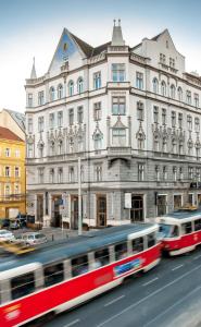 un bus rouge et blanc passant devant un bâtiment dans l'établissement Czech Inn, à Prague