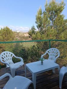 two white chairs and a table on a deck at Cabaña conteiner Aires de Mar in Huerta Grande