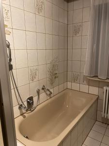 e bagno con vasca e piastrelle bianche. di Restaurant Pizzeria & Fremdenzimmer Laquila zum Adler a Salach