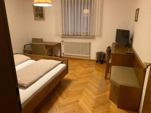 una camera da letto con un letto, una scrivania e una televisione di Restaurant Pizzeria & Fremdenzimmer Laquila zum Adler a Salach