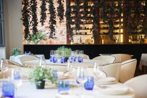 a dining room with white tables with blue glasses at La Casa Azul Boutique Hotel in Andújar