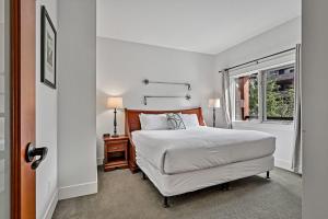 een witte slaapkamer met een bed en een raam bij Classic Hideaway Elegant 2BD 2BTH in Canmore