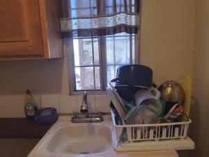 a kitchen sink with a dish drying rack next to a window at Pequeña casa vacacional en Ensenada Mx in Ensenada