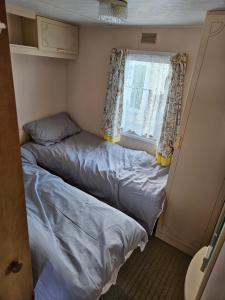 two beds in a small room with a window at Ingoldmells golden sands plot 152 in Ingoldmells