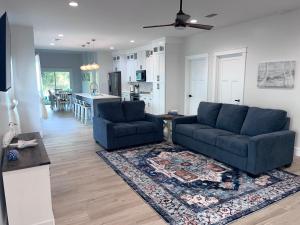 ein Wohnzimmer mit 2 blauen Sofas und einer Küche in der Unterkunft Beachy cottage near Sports Complex OWA beaches shopping restaurants mini golf Central to all the fun Foley has to offer in Foley