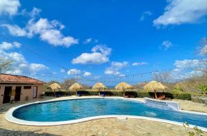 a swimming pool with umbrellas and a blue sky at Villas de Palermo Hotel and Resort -Private Detached Houses in San Juan del Sur