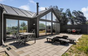 a patio with a table and chairs and windows at Lovely Home In Blokhus With Sauna in Blokhus +28 photos