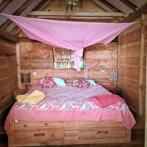 a bedroom with a bed in a wooden cabin at L'Auberge Polynésienne in Tevaitoa