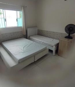 twee bedden in een kamer met een raam bij Casa com piscina in Peruíbe