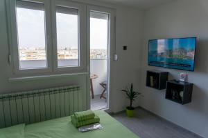 a bedroom with a bed and a tv and windows at Studio Apartment-Horizont 47 in Novi Sad