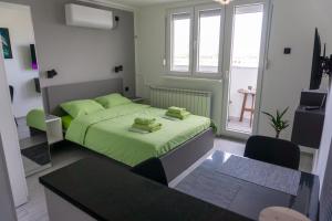 a small bedroom with a green bed and a table at Studio Apartment-Horizont 47 in Novi Sad