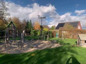 a playground in a park with a barn and a house at Vakantiehuis op Villapark Oesterbaai aan zee , met speeltuin grenzend aan de tuin in Wemeldinge