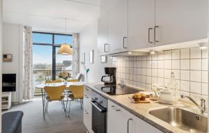 a kitchen with white cabinets and a table with chairs at Fanø Bad, Lejl 74 in Fanø