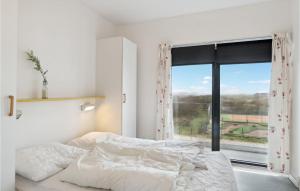 a white bedroom with a bed and a large window at Fanø Bad, Lejl 74 in Fanø +8 photos