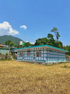 a blue building with a field in front of it at BASERAA BIR - A Slow Traveler's Home in Bīr